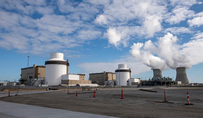 A nuclear power facility with cooling towers emitting clouds of steam into the sky