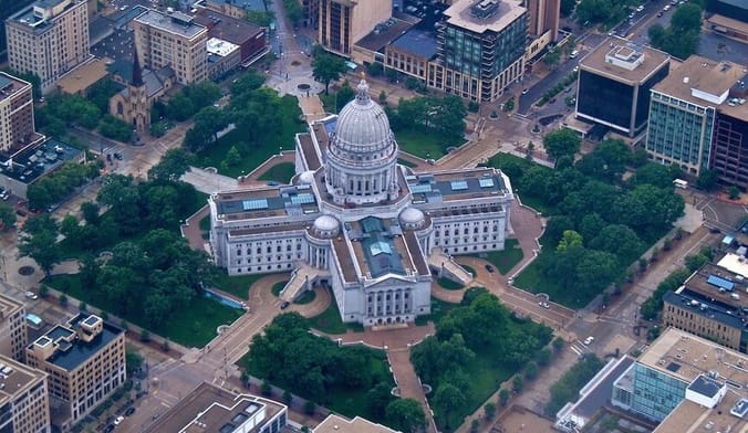 An aerial view of a large white building in a cross formation topped by a large rotunda
