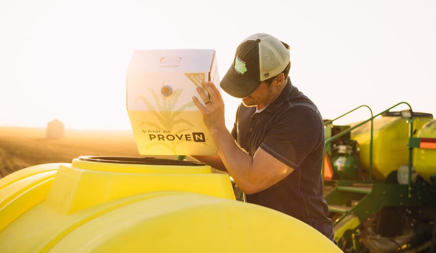 a man pours contents of a bag labeled proven into a cylindrical yellow bin