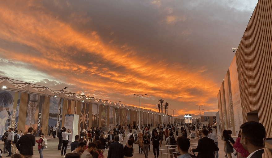 A large crowd of COP27 attendees outside at sunset