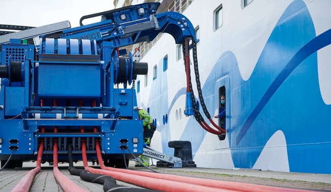 a large red and blue plug is getting connected to a cruise ship in port