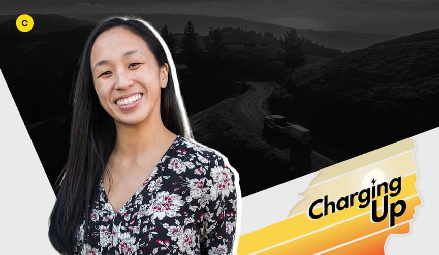 A smiling Asian woman with long black hair wearing a black shirt with a floral pattern. Graphic overlay says CHARGING UP