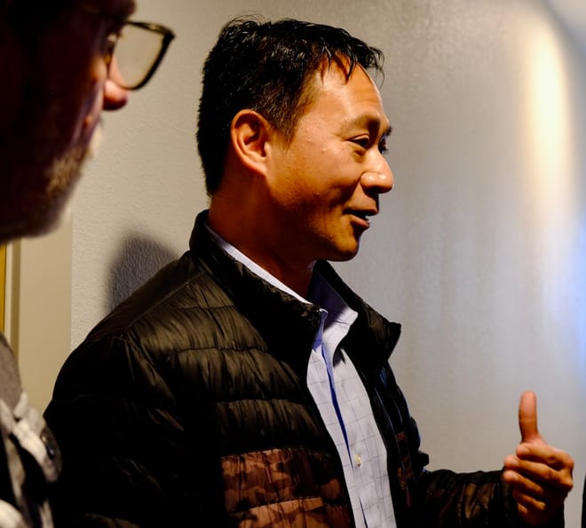 A man with short black hair and puffy jacket talks through a smile explaining about the climate technology in a Geos home.