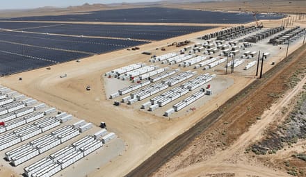 Aerial view of a solar project with large batteries in the desert.