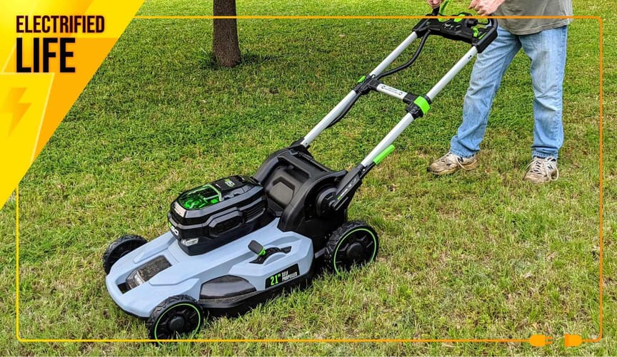 Person wearing jeans and dirty tennis shoes pushes Ego-brand electric lawn mower.