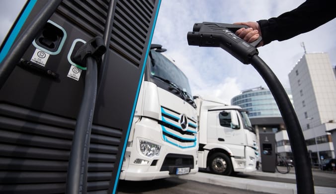 hand with charger, large trucks in the background