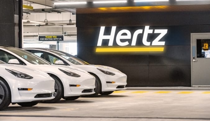 A row of white cars in a hertz airport parking lot