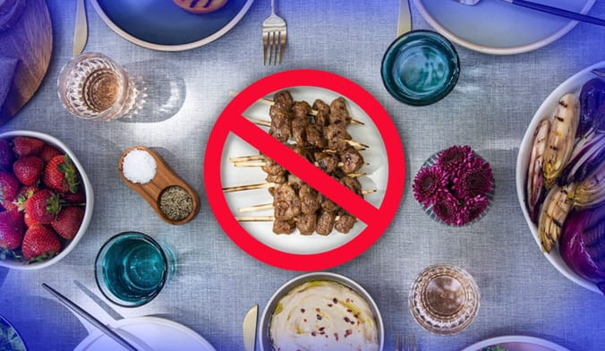 an overhead view of a table set with many dishes of food. A plate of meat skewers at center has a red prohibition sign on it.