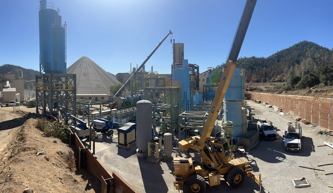 AN outdoor industrial site with tractors, scaffolding, storage tanks and other equipment