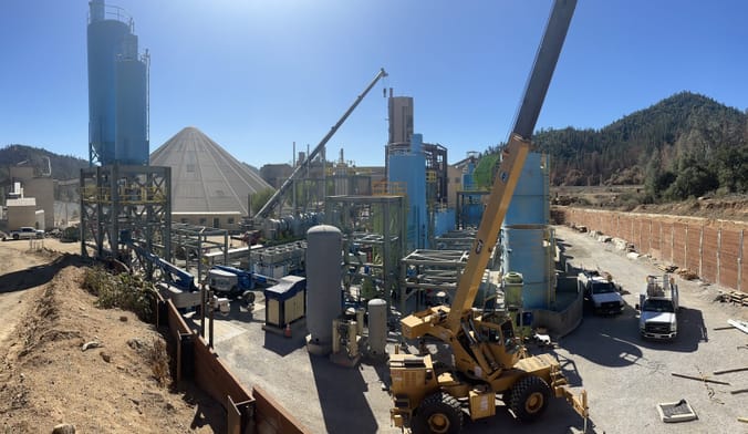 AN outdoor industrial site with tractors, scaffolding, storage tanks and other equipment