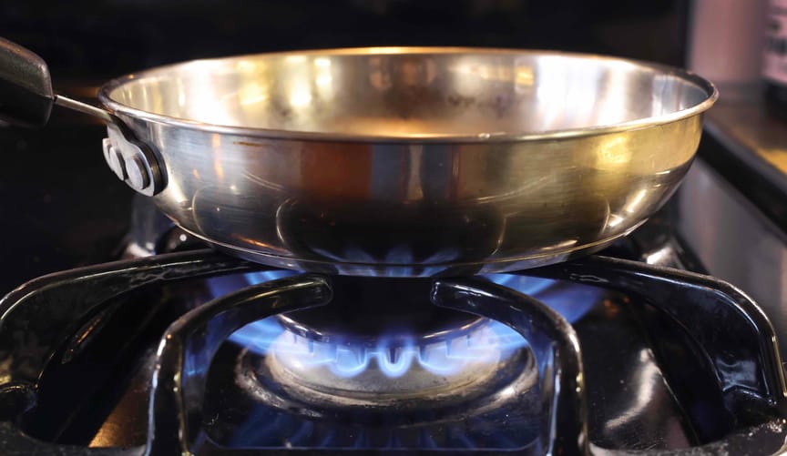 A pan sits on flames burning on a natural gas-burning stove