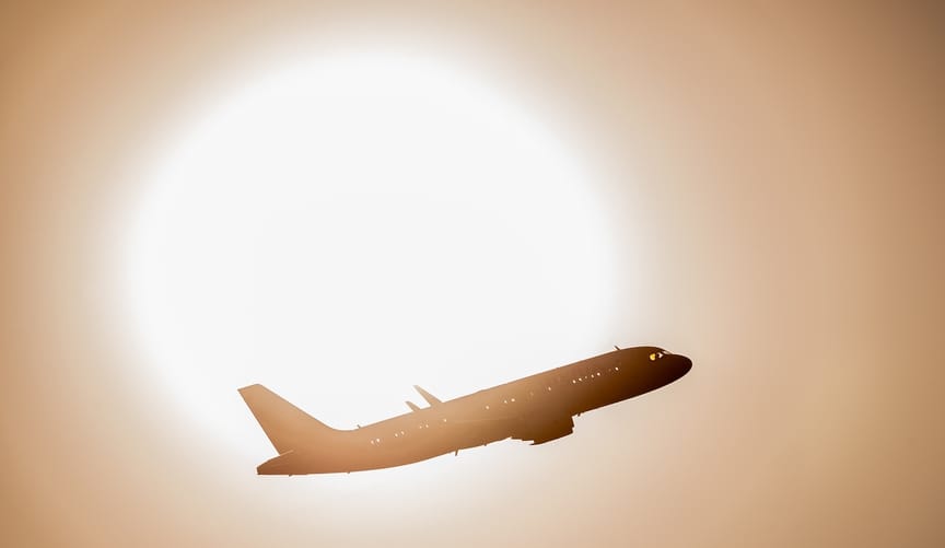 plane ascending in front of sun
