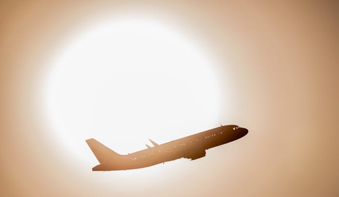 plane ascending in front of sun