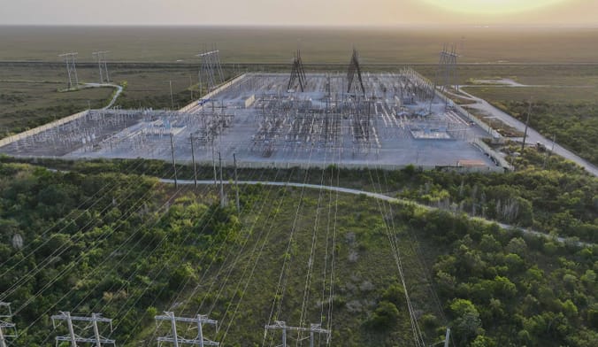 In an aerial view, high voltage power lines run along the electrical power grid