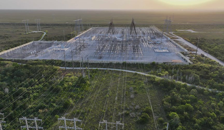 In an aerial view, high voltage power lines run along the electrical power grid