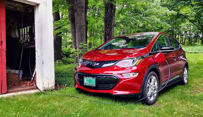 Electric vehicle plugged into charging cord outside a barn in Vermont