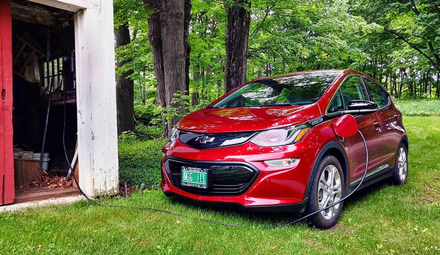 Electric vehicle plugged into charging cord outside a barn in Vermont