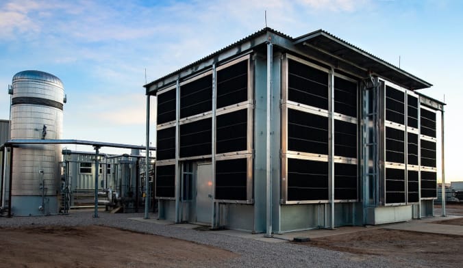 A tall building with black air-filter panels stands against a blue sky