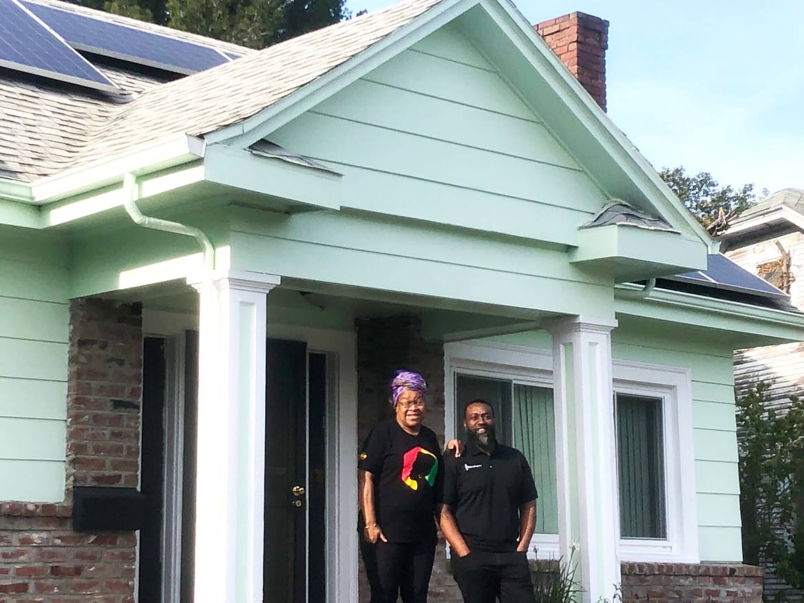 Oakland homeowner Cheryl Ajirotutu and Mark Hall, CEO of Revalue.io, in front of Ajirotutu's all-electric home