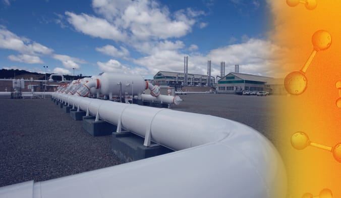 In the foreground is a long white pipeline. In the background are compressor pumps and an industrial facility.