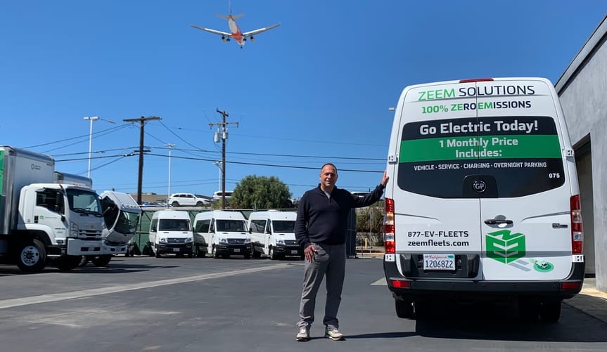 Zeem CEO Paul Gioupis shows off an electric van available for lease as a plane descends to nearby LAX.