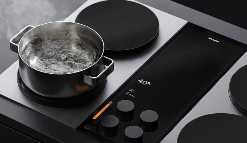 A pot of water boiling atop a sleek silver and black induction stovetop