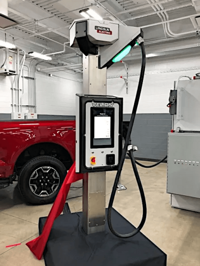 A sleek silver metal EV charger inside an industrial garage facility