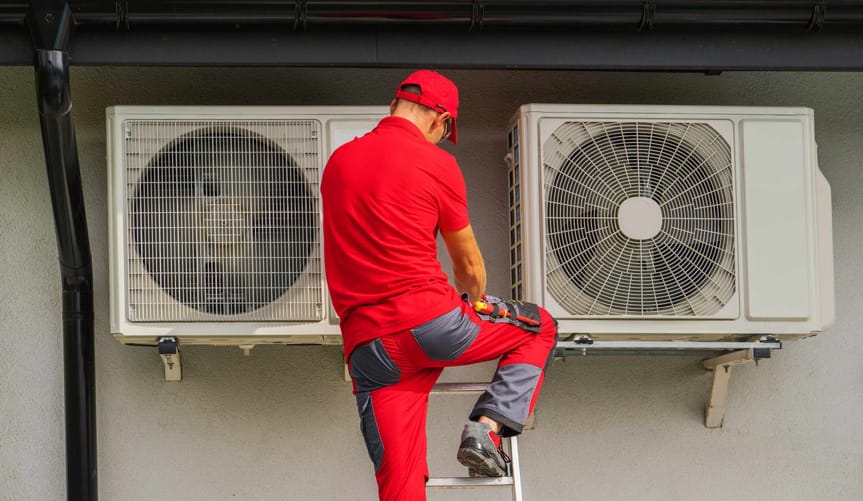 An HVAC technician working on heat pump units