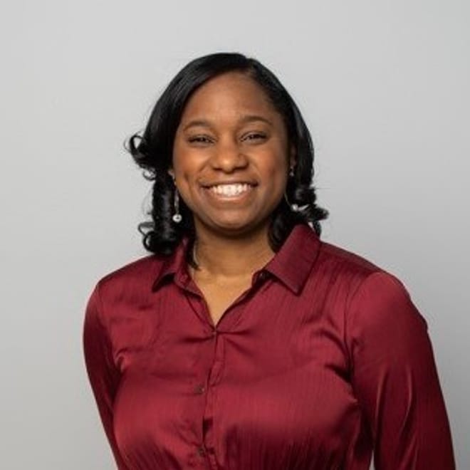 A smiling Black woman with shoulder-length dark hair and a burgundy top