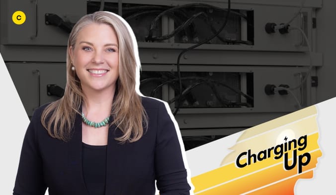 A smiling white woman with light hair wearing a black blazer and turquoise necklace next to a graphic that says charging up