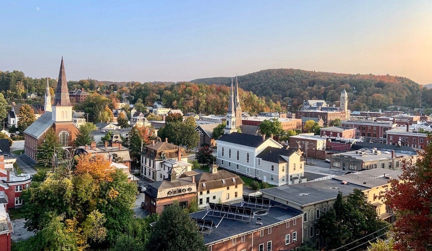 Red brick buildings, church steeples and orange-and-green trees are shown in an overhead view of Montpelier, Vermont.