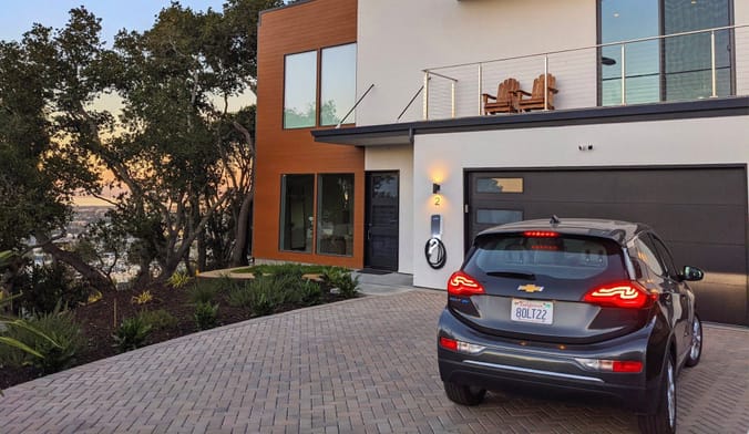 A black EV in the driveway of a modern two-story home