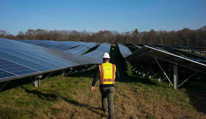 worker in a field of solar panels