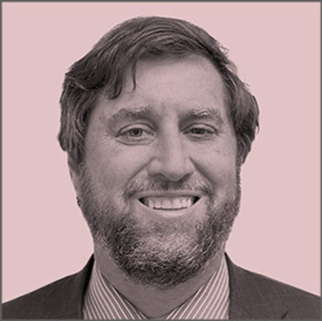 A smiling man with a beard in a pink-tinted photo