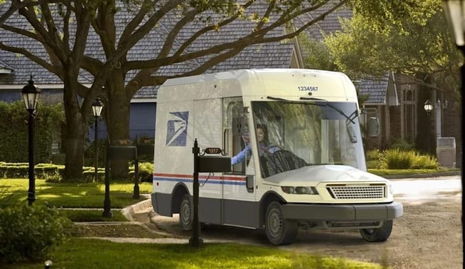 A postal worker inserts mail into a residential mailbox while driving an electric postal delivery truck