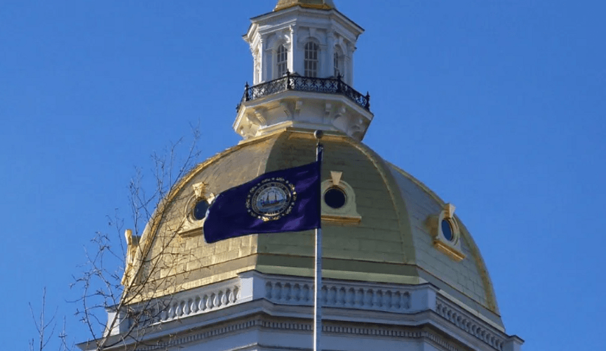 A dark blue flag flies in front of a golden cupola against the backdrop of a bright blue sky