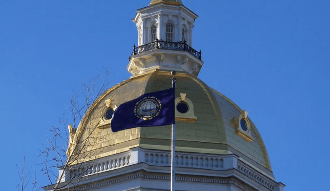 A dark blue flag flies in front of a golden cupola against the backdrop of a bright blue sky