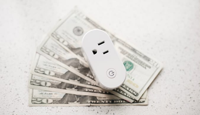 OhmConnect smart plug on top of pile of $20 bills