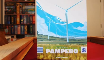 Board game box that says Pampero sits on a red billiard table, with wall of board games in background.