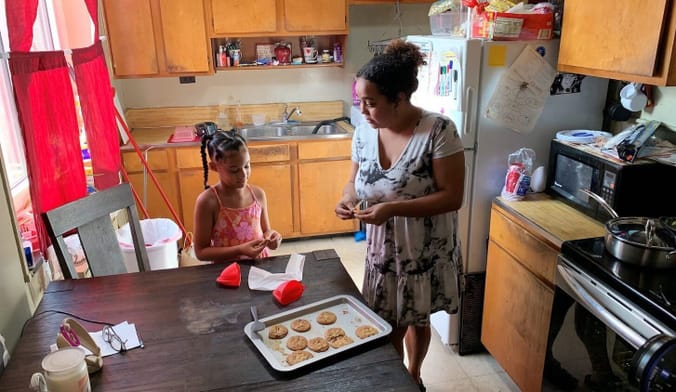 A mother and daughter bake cookies in their kitchen with an electric oven