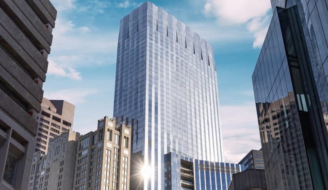 A gleaming window-clad skyscraper soars amid shorter buildings.