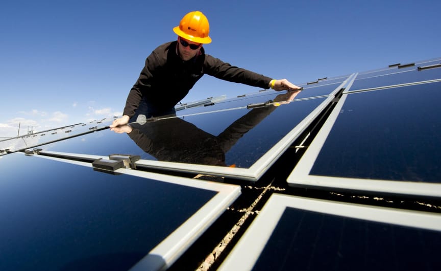 A worker in a hard hat installs a solar panel