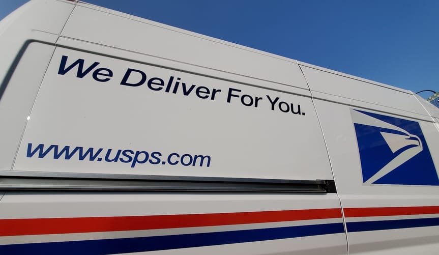 Side of US postal service van with slogan "We deliver for you".