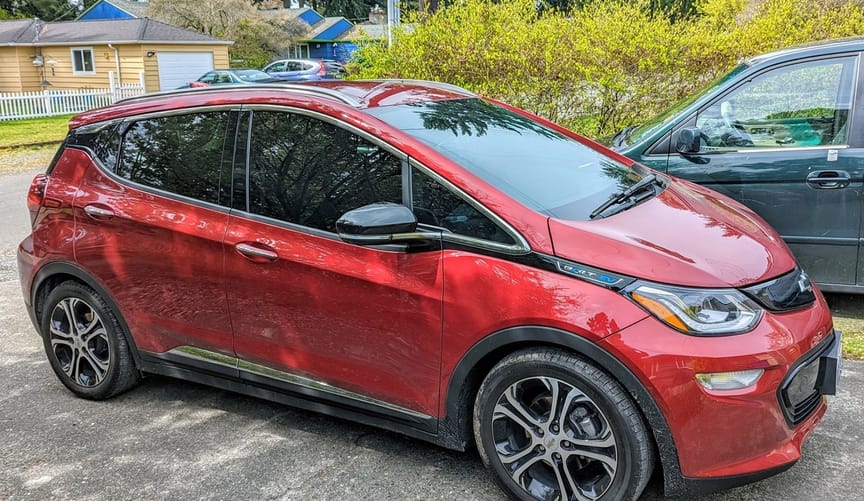 A red four-door electric vehicle in a parking lot