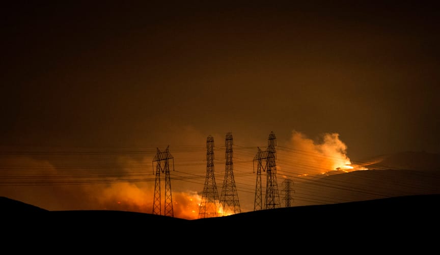 Clouds of smoke arise from a fire near transmission lines