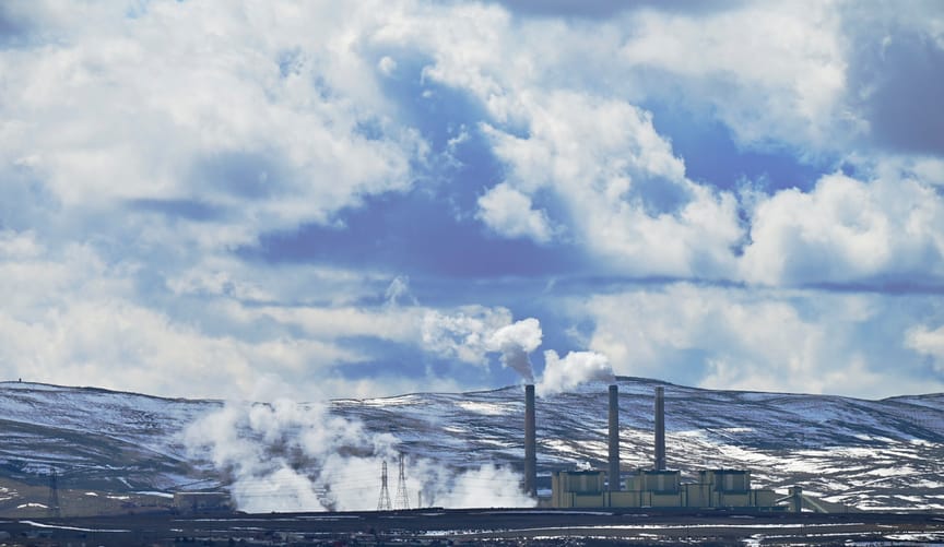 A large coal-fired power plant next to snowy foothills