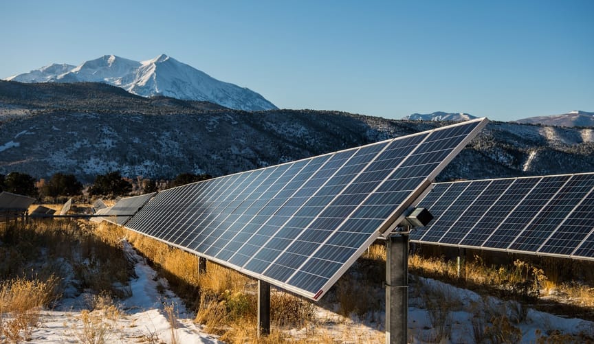 A solar panel array in front of a snowy mountain