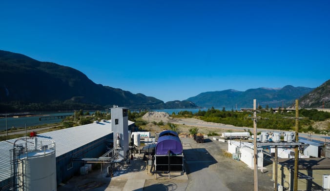 A carbon removal site showing industrial equipment and facilities against a backdrop of a forested mountain range
