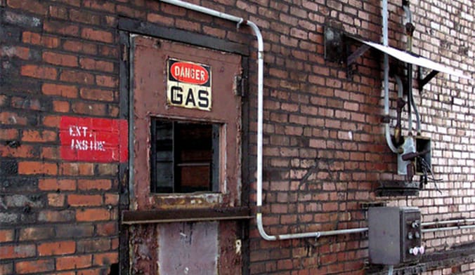 A brick building with a sign that says danger gas over the door