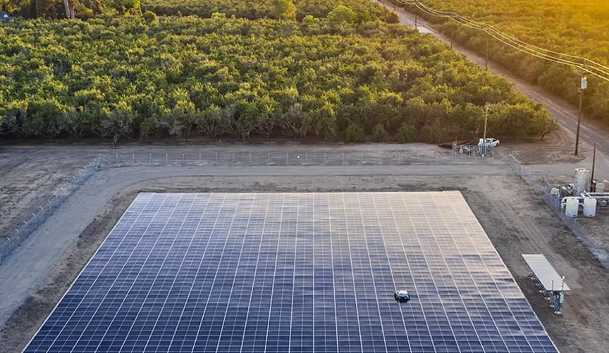 A solar array in a wooded rural area. the panels are mounted directly on the ground.